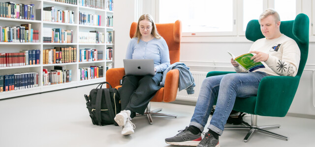 Kaksi opiskelijaa istuu nojatuoleissa Arcanumin kirjastossa
