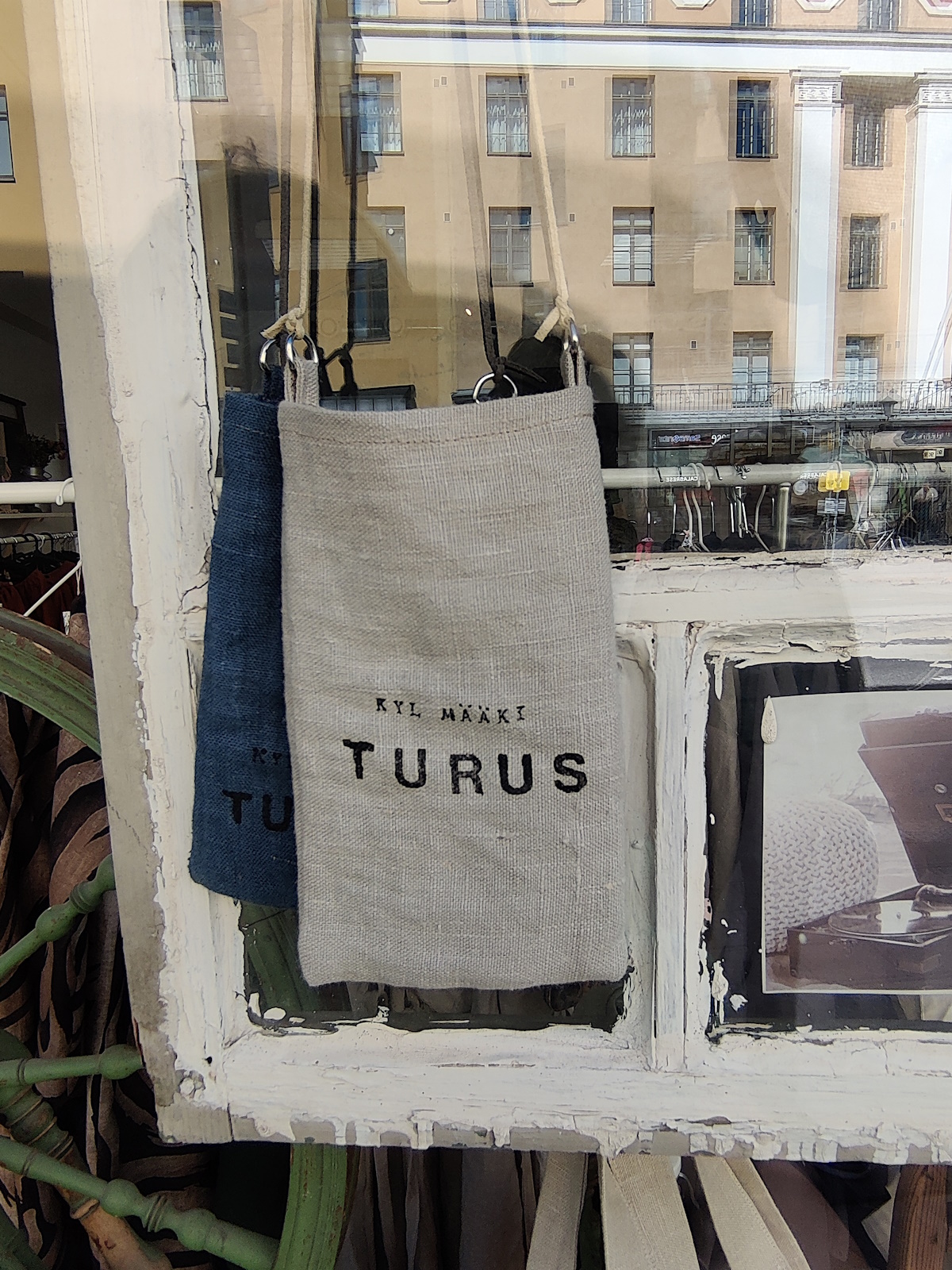 Liikkeen näyteikkuna Linnankadulla, vanha ikkunankehys ja juuttikasseja joissa lukee "kyl määki Turus"