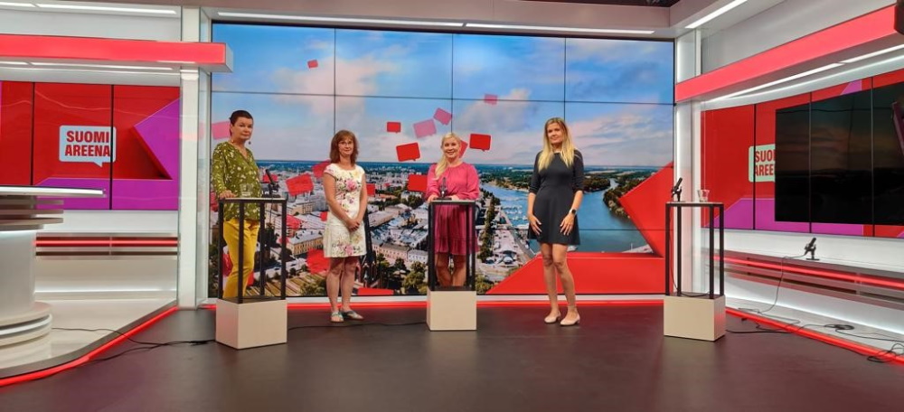 Neljä henkilöä seisoo studiossa, jossa on punaiset seinät.