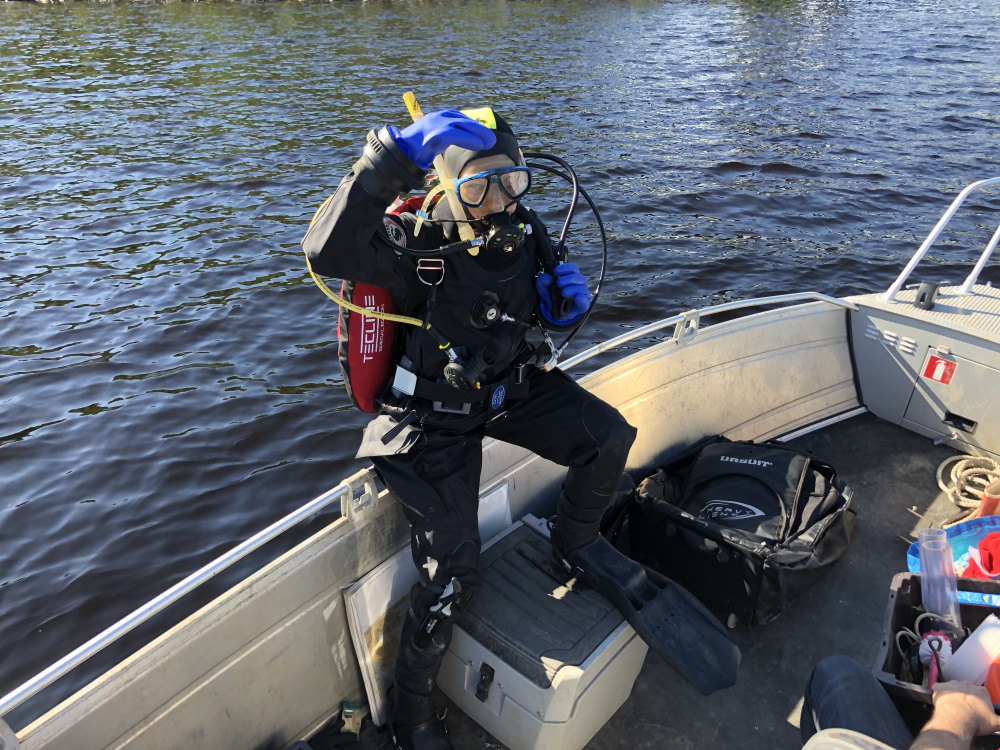 Saija Saarni veneessä sukelluspuvussa hyppäämässä veteen.