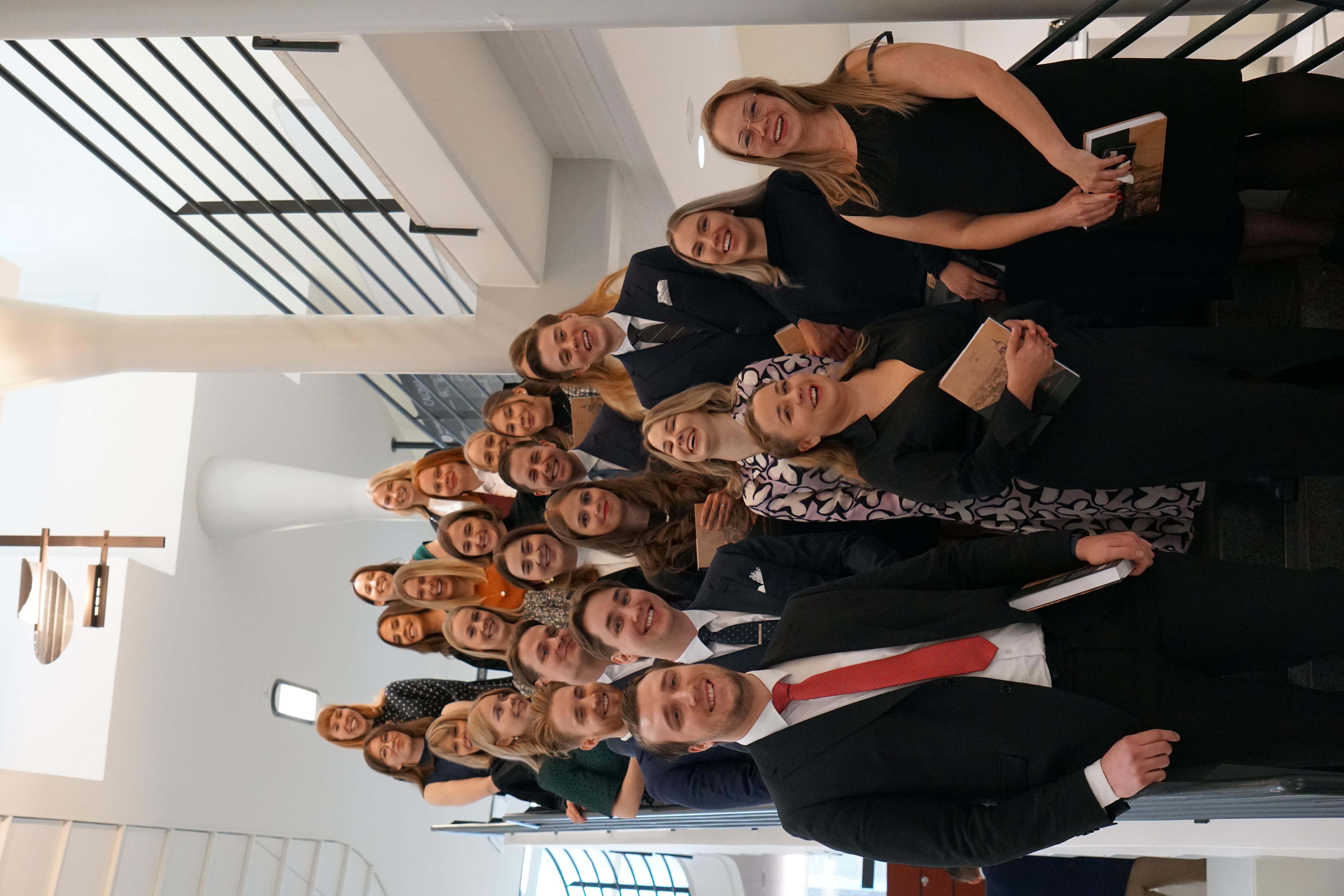 Iloiset vastavalmistuneet oikeustieteen maisterit yhteiskuvassa publiikissa 8.12.2023