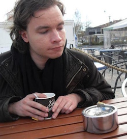 J. J. Rintala istuu ulkona pöydän ääressä.