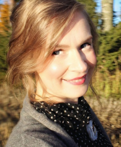 Katrina Virtanen lähikuvasssa ulkona, taustalla metsää.