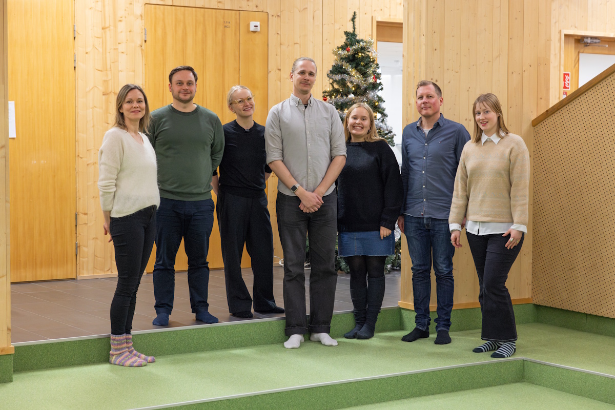 Naisia ja miehiä yhteiskuvassa hymyilemässä kameralle.