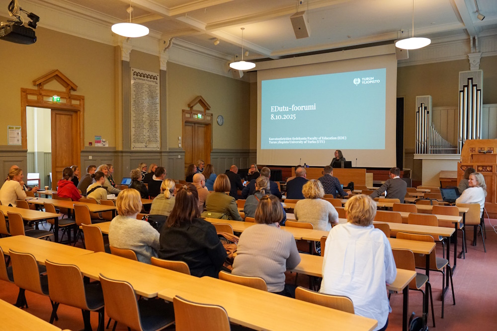 Ihmisiä kuuntelemassa puhujaa luentosalissa.