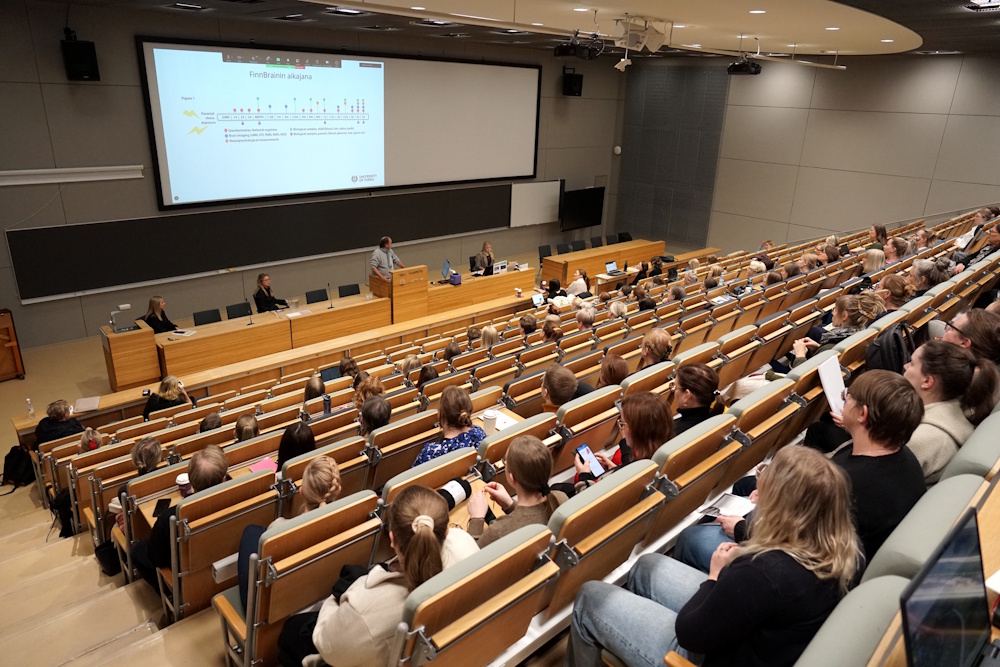 Luentosali täynnä ihmisiä kuuntelemassa seminaaria