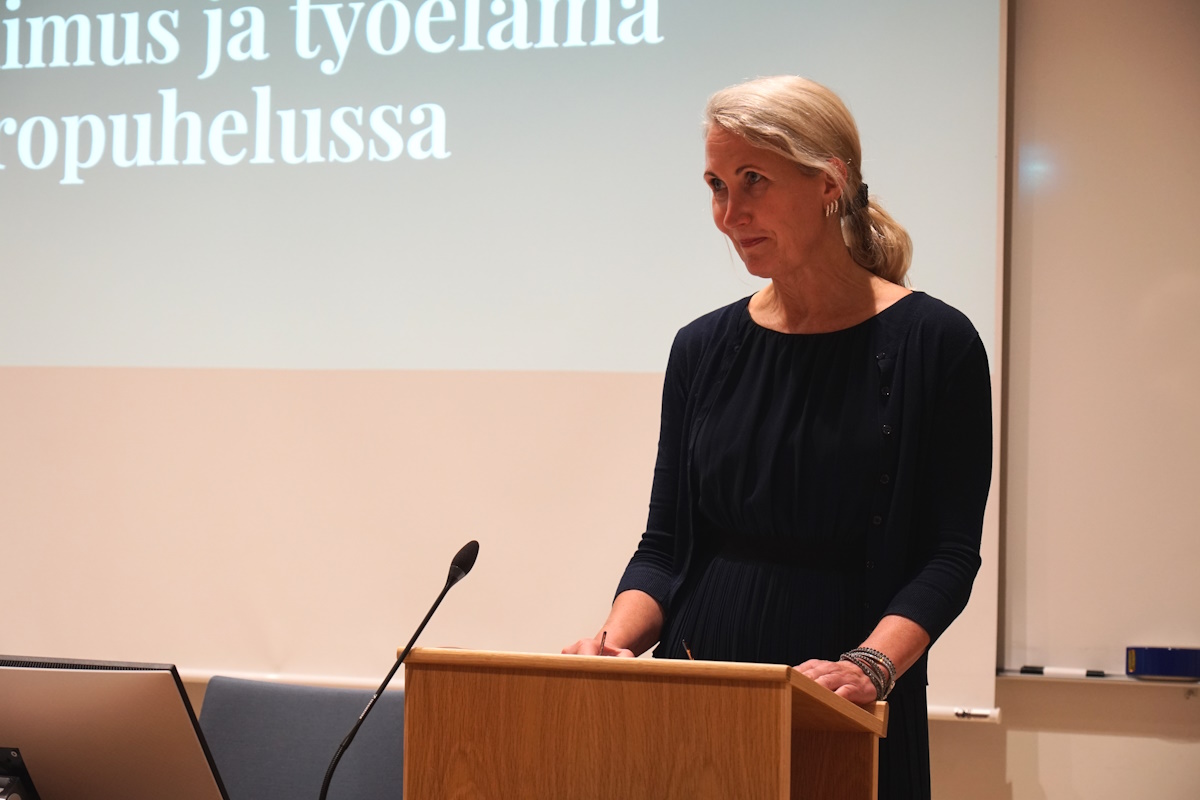 Nainen puhuu tilaisuudessa puhujapöntön takana.