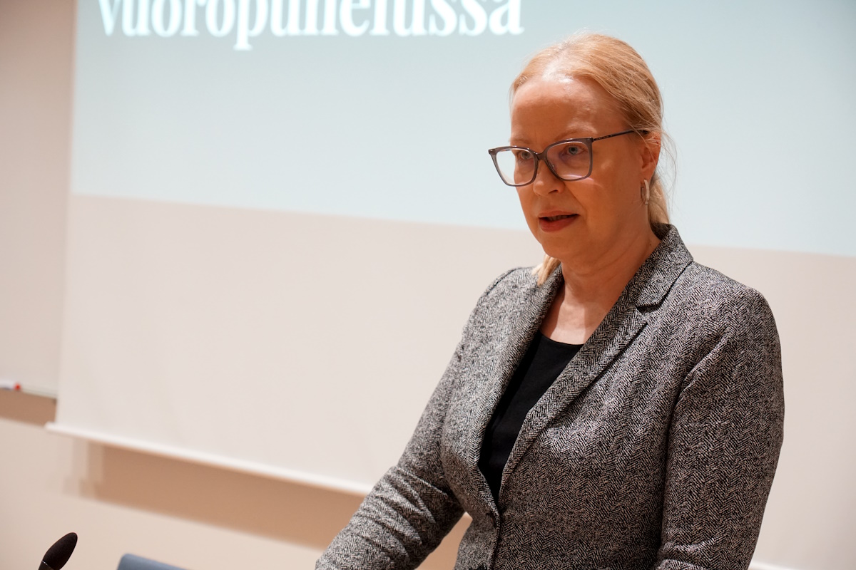 Nainen puhuu tilaisuudessa puhujapöntön takana.