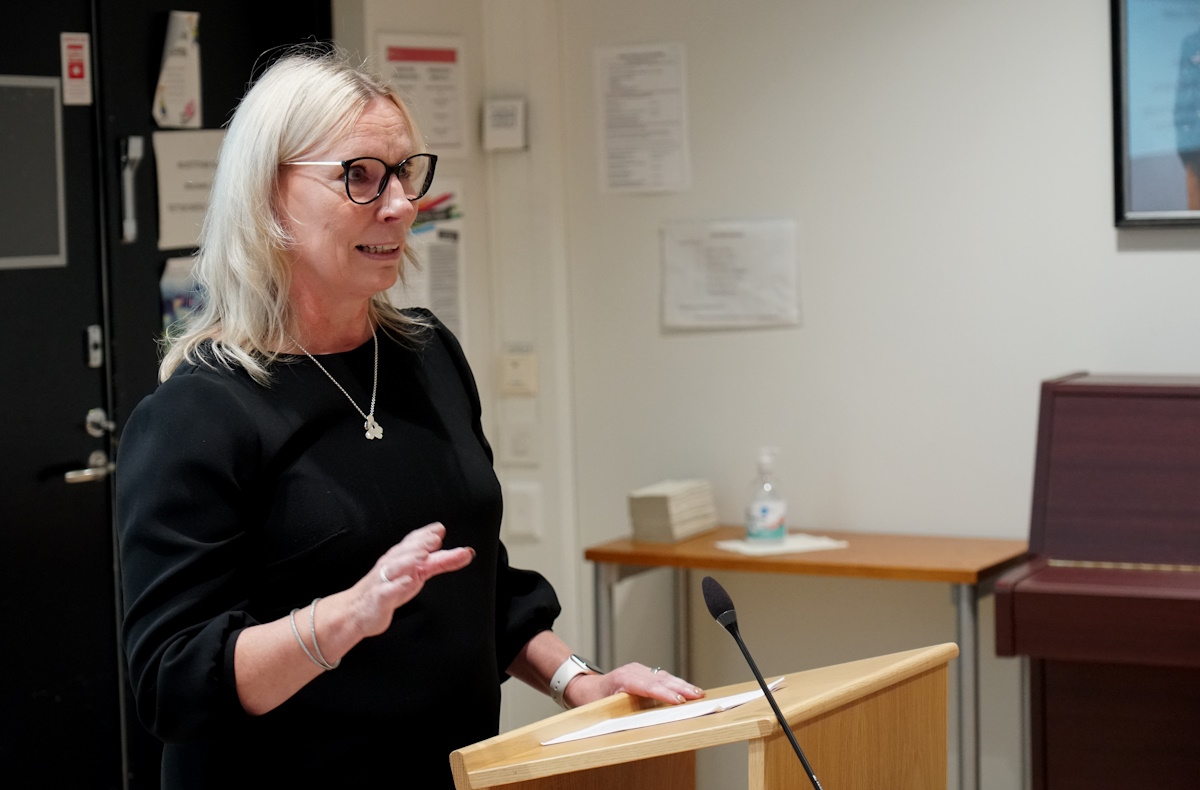 Nainen puhuu tilaisuuden kuulijoille.