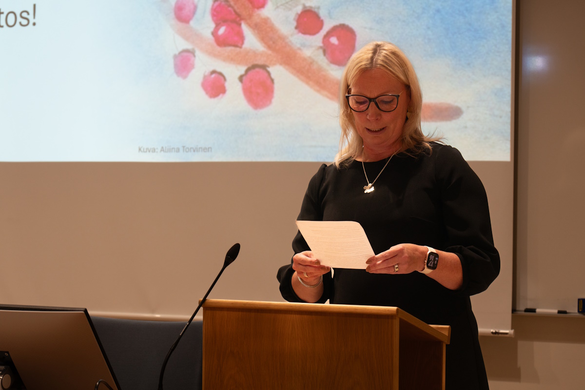 Nainen lukee tekstiä paperilta ihmisille..