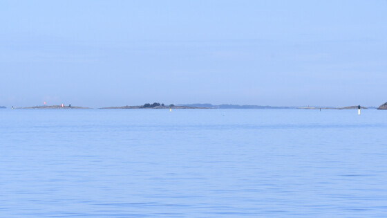 Utuinen merimaisema, jossa horisontissa näkyy saari ja merimerkkejä