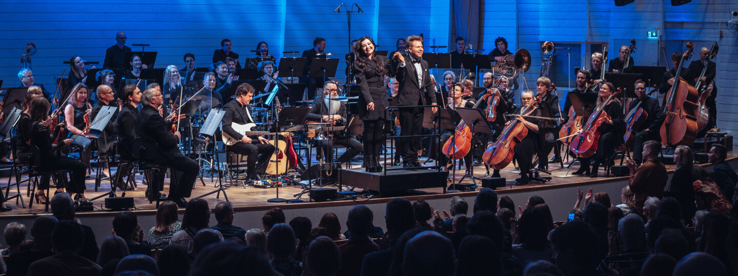 Diandra ja kapellimestari Antti Rissanen vastaanottavat yleisön suosionosoitukset Turun filharmonisen orkesterin ympäröimänä.