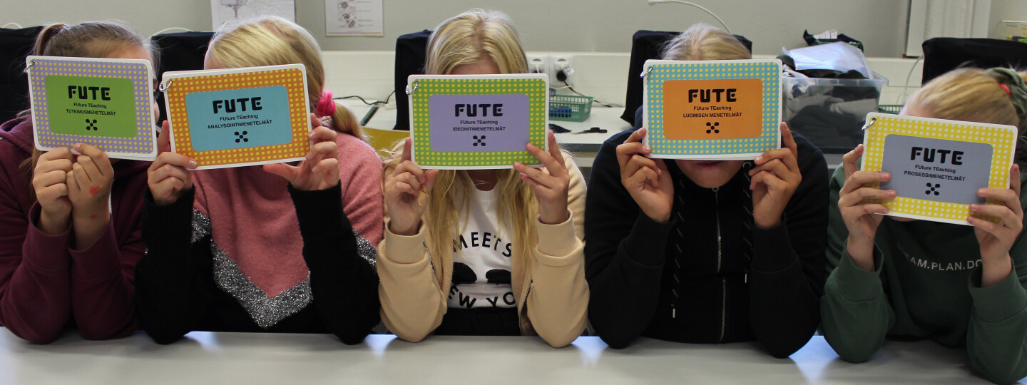 Oppilaat pitävät kasvojen edessä FUTE-mentelmän kortteja