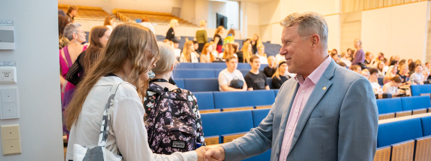 Rehtori Jukka Kola kättelee uutta opiskelijaa tervetulotilaisuudessa