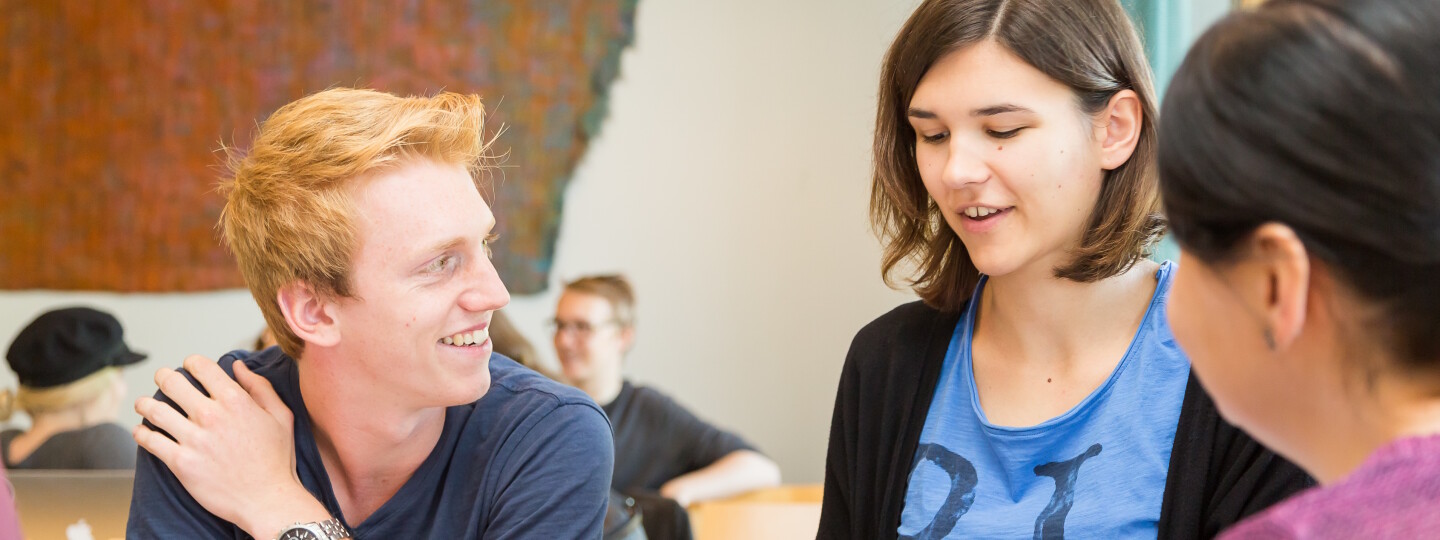 Kolme opiskelijaa keskustelee tehtävästä