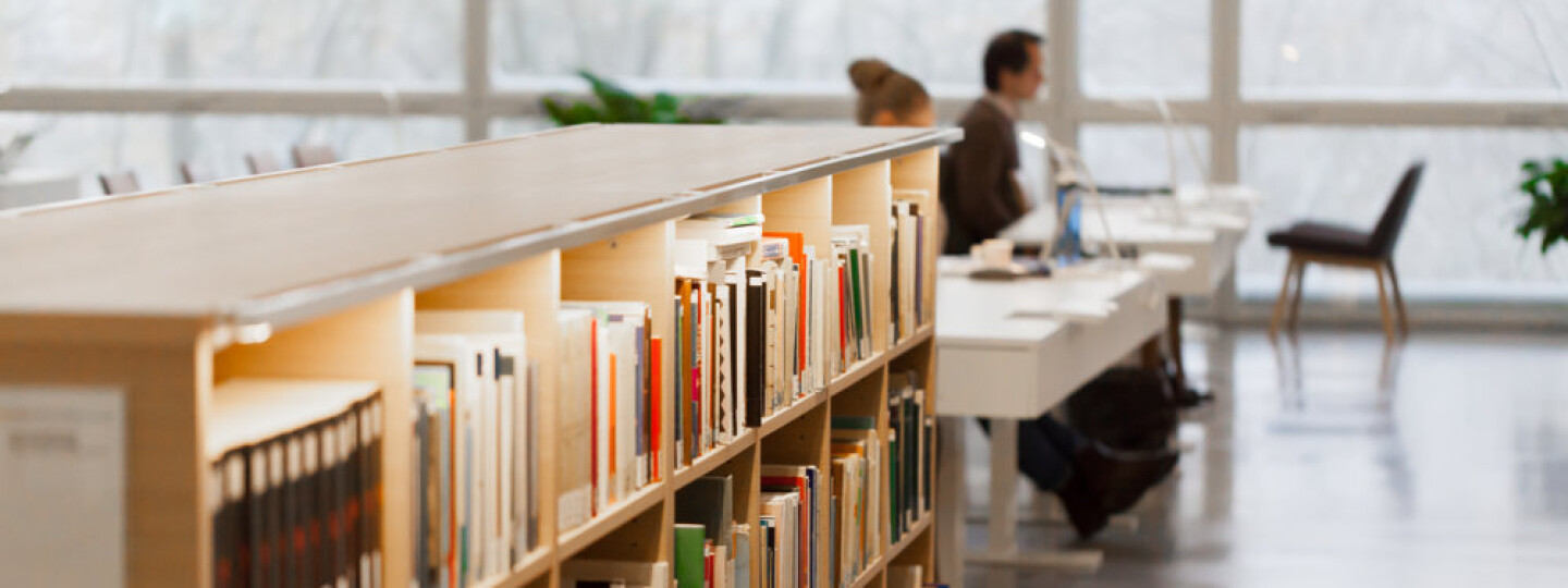 Kirjoja valaistussa hyllyssä kirjastossa.