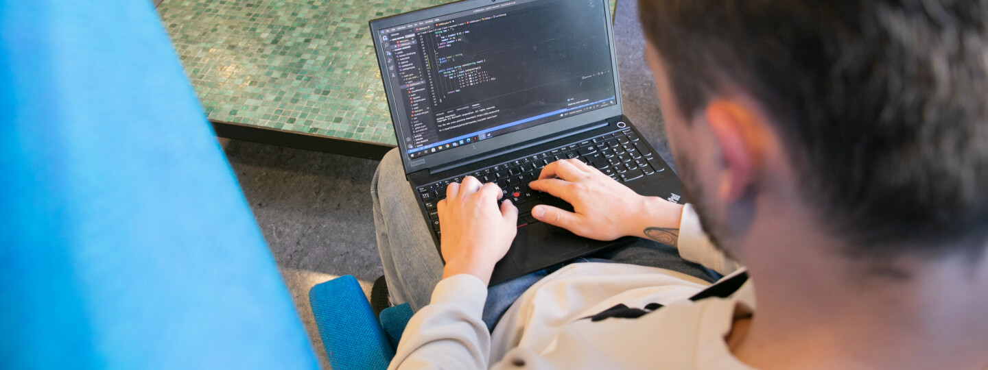 Opiskelija työstää koodia kannettavalla tietokoneella.