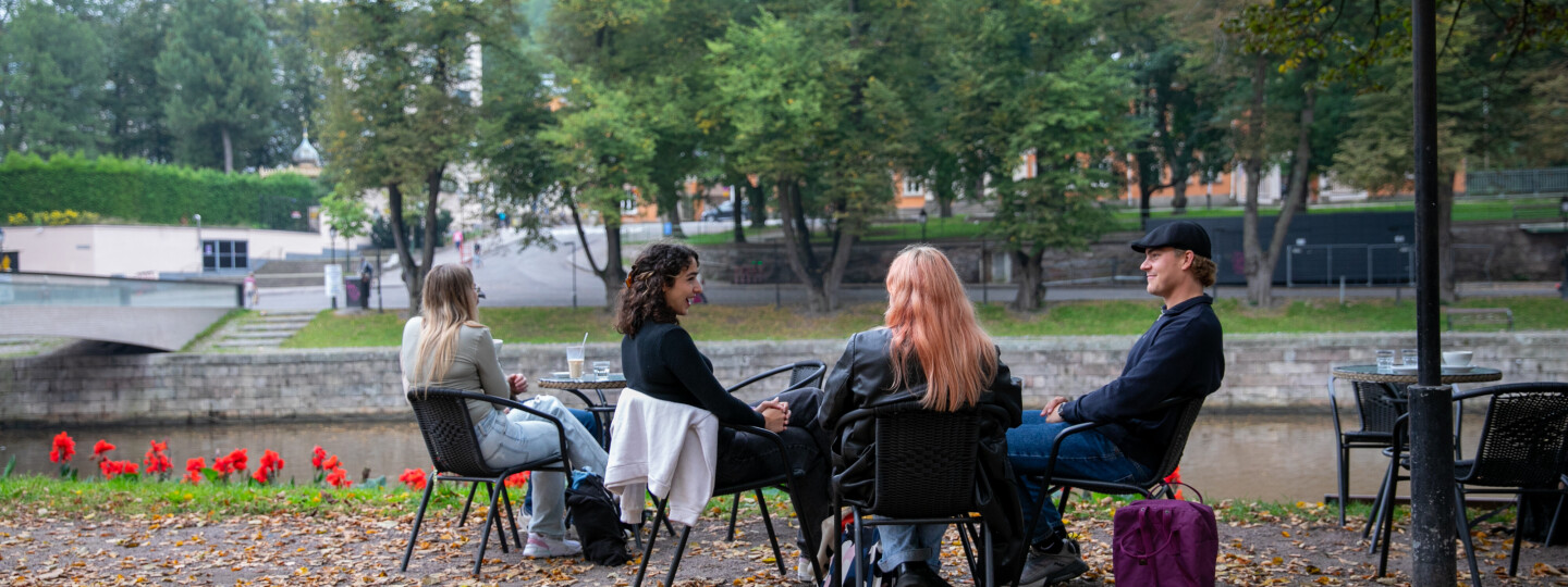 Ryhmä opiskelijoita istuu kahvilla ulkona.