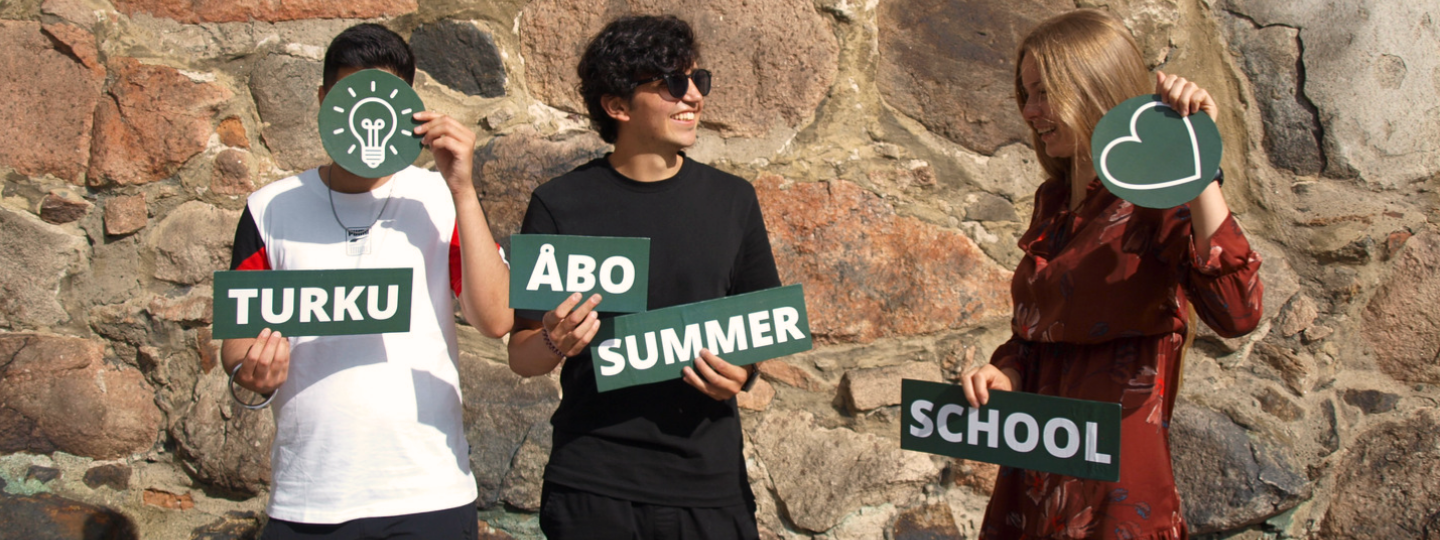 three students holding turku åbo summer school signs