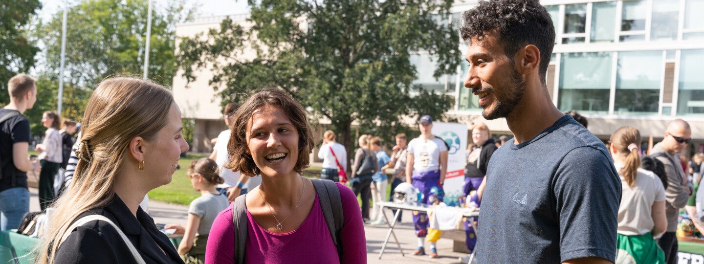 three students chatting in the campus square