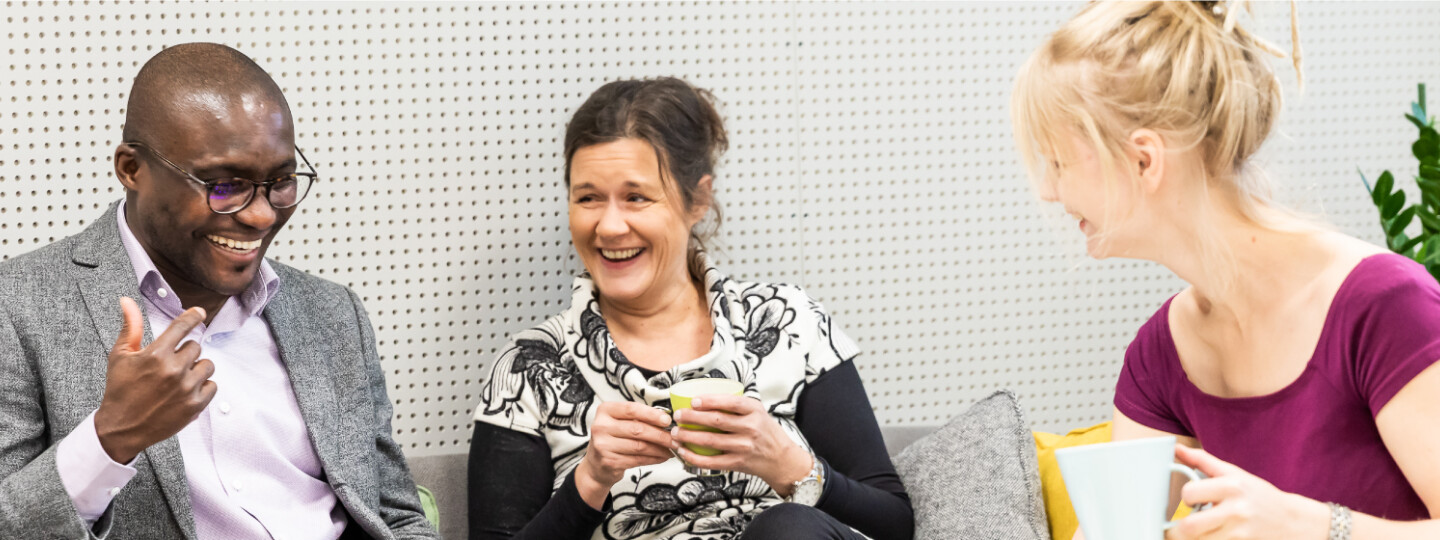 Henkilöstöä istumassa ja nauramassa. Kuvituskuva