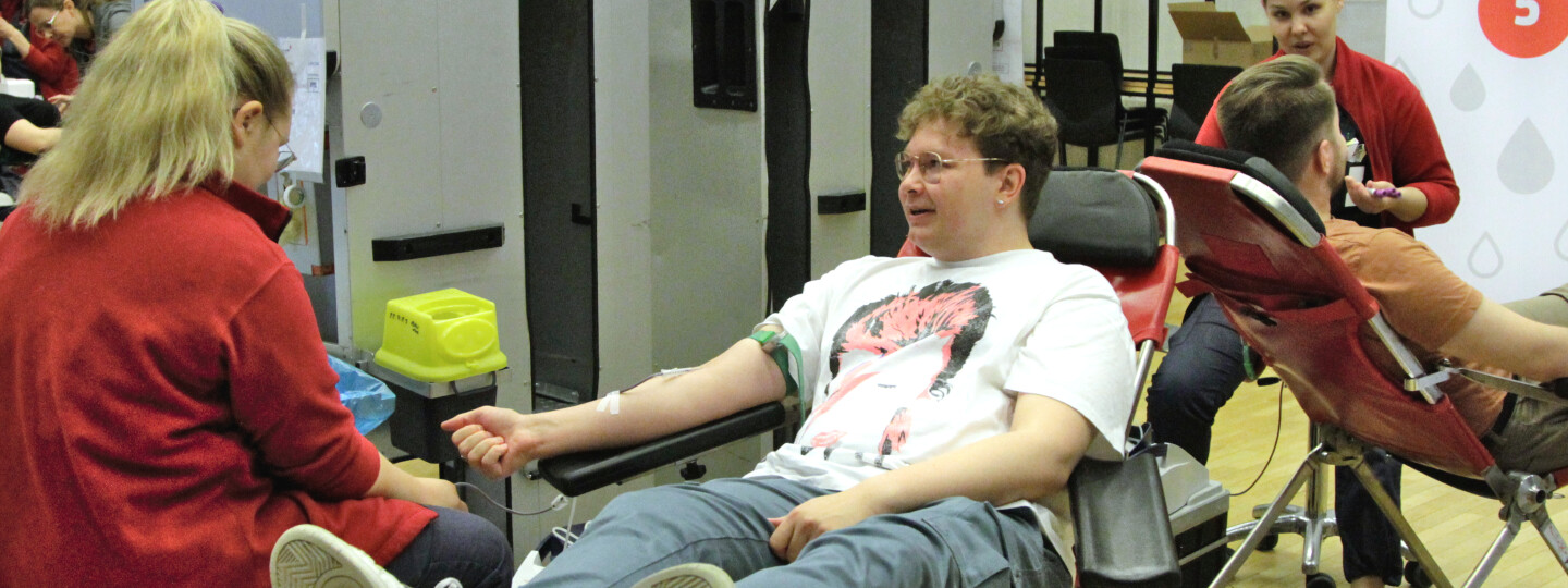 Opiskelija istuu hoitajaa vastapäätä verenluovutuspenkissä