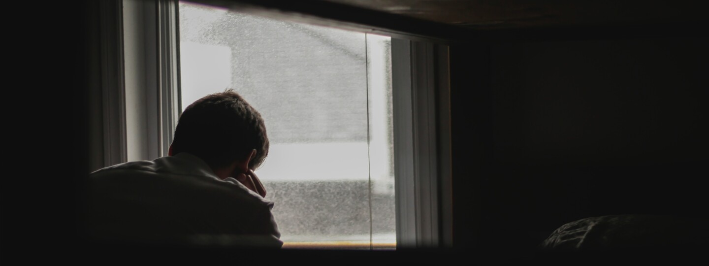 Nuori henkilö istuu ikkunan äärellä.