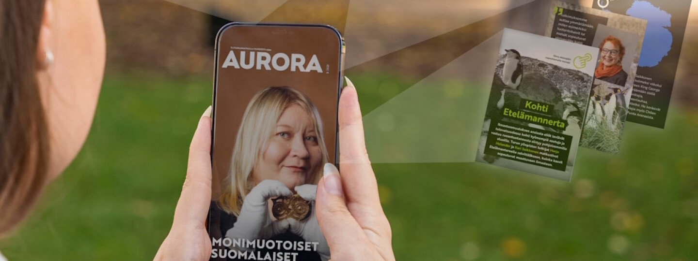 Ihminen pitää puhelinta, jossa näkyy Aurora-lehden kansi ja puhelimen ympärillä erilaisia verkkosisältöjä.