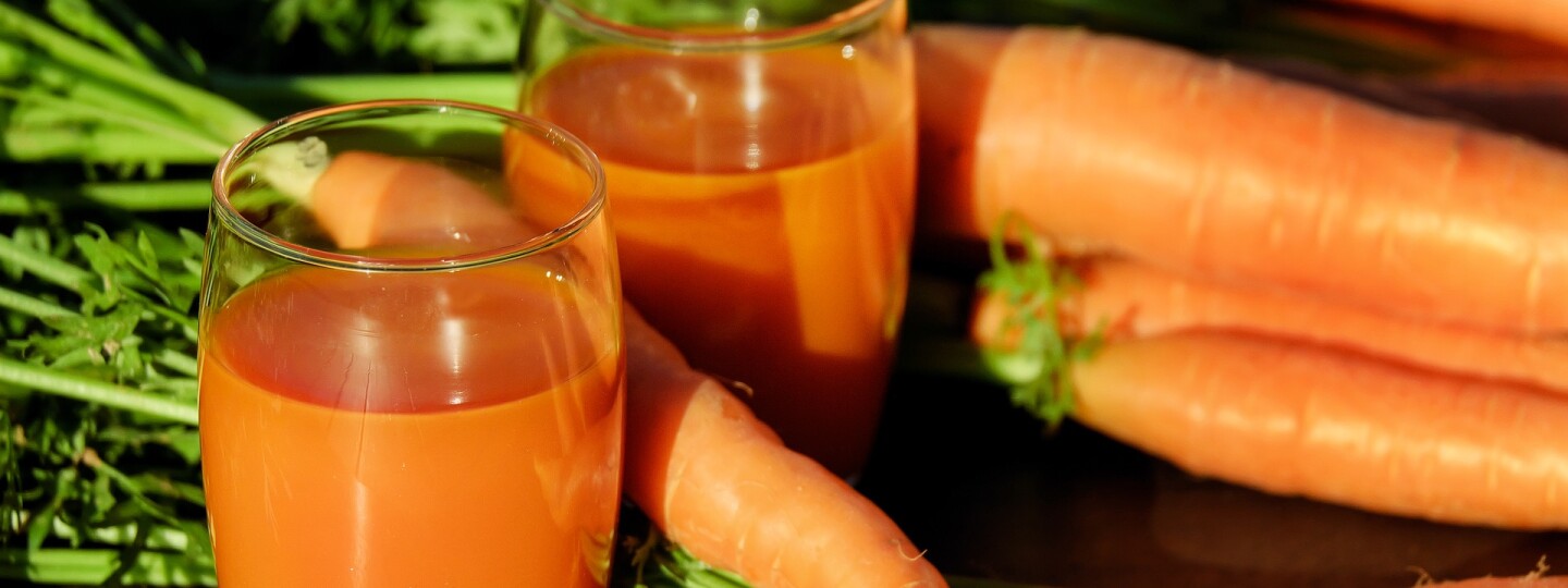 Porkkanoita sekä lasissa niistä valmistettua mehua.