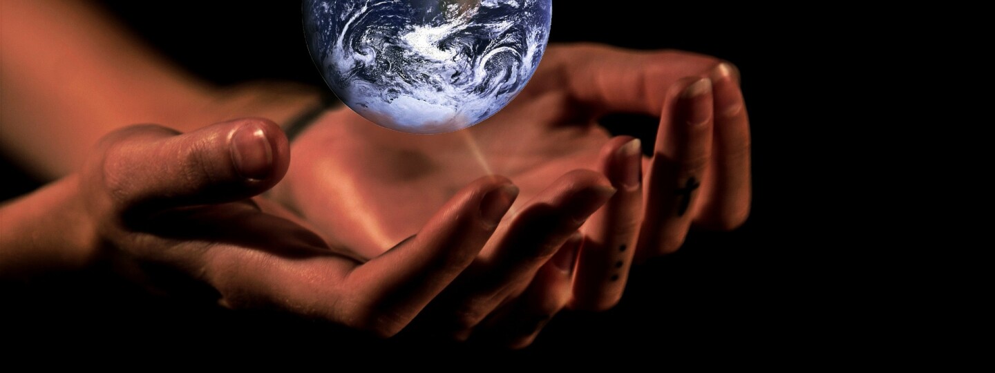Leijuva maapallo, jonka alla ihmisen kädet kannattelevassa asennossa.