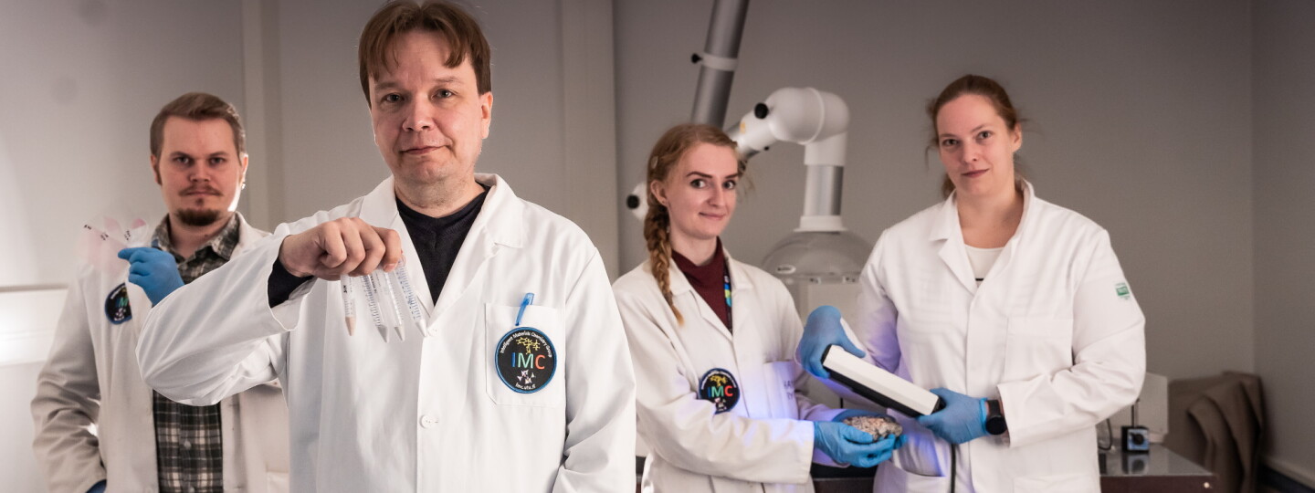 Sami Vuori, Mika Lastusaari, Hannah Byron ja Isabella Pönkkä laboratoriossa valkoiset takit yllään ja tavaroita käsissään.
