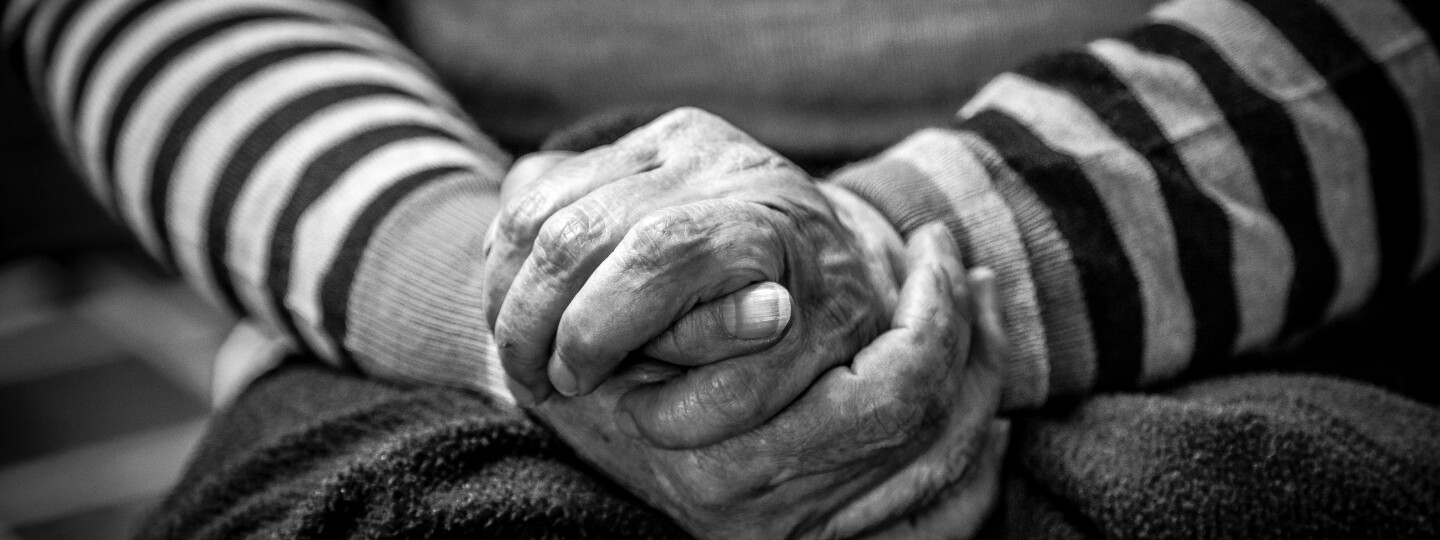 Mustavalkoinen kuva, jossa ikääntyneen henkilön kädet