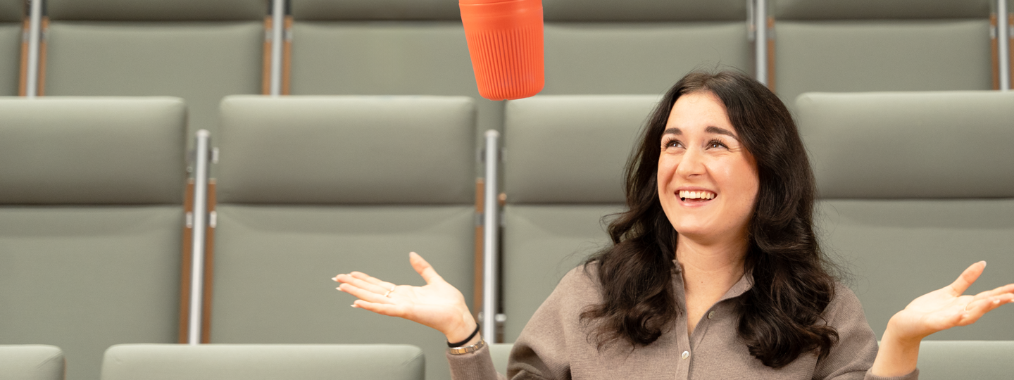 Henkilö luentosalissa katsomassa yllättyneenä kun hänen mukinsa leijuu. 