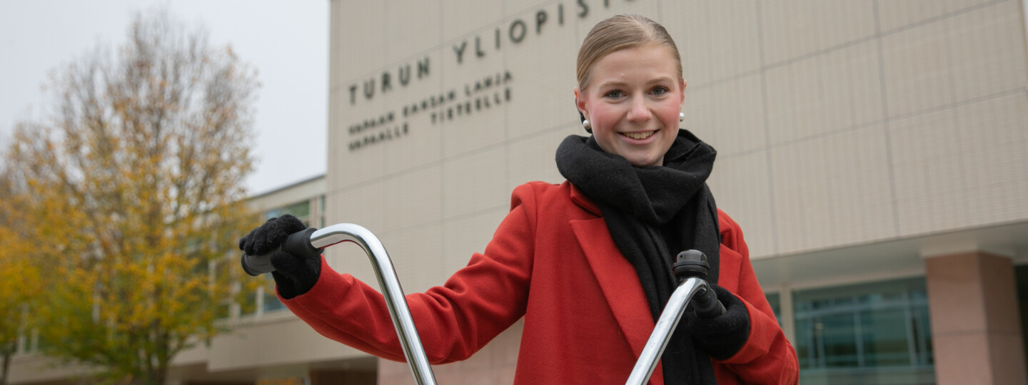 Nainen pyörän kanssa Turun yliopiston päärakennuksen edessä