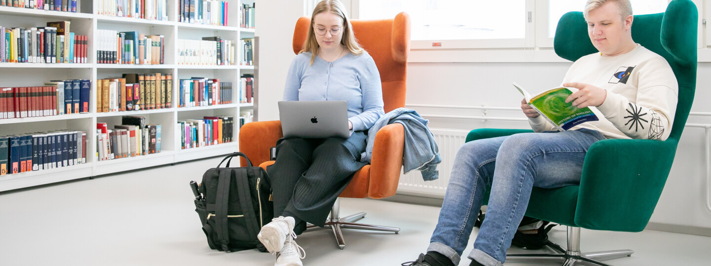 Kaksi opiskelijaa istuu nojatuoleissa Arcanumin kirjastossa