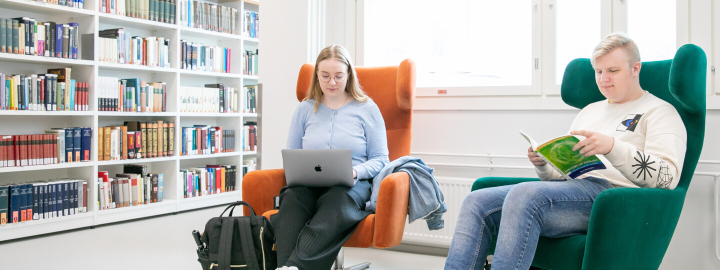 Two students sitting in armchairs in the Arcanum Library