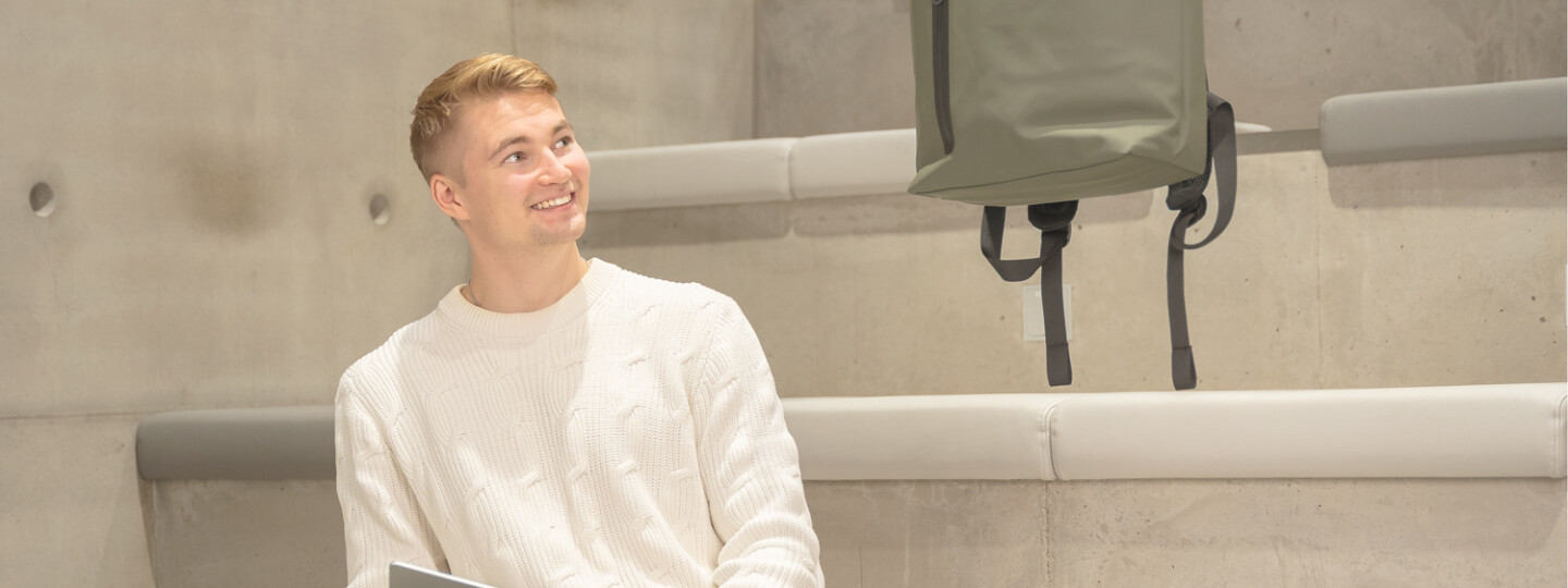 Henkilö katsoo iloisesti leijuvaa reppua.