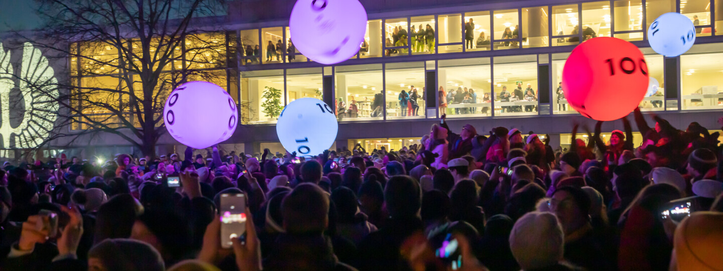 Yleisö heittelee 100-vuotisvalopalloja Yliopistonmäen aukiolla.