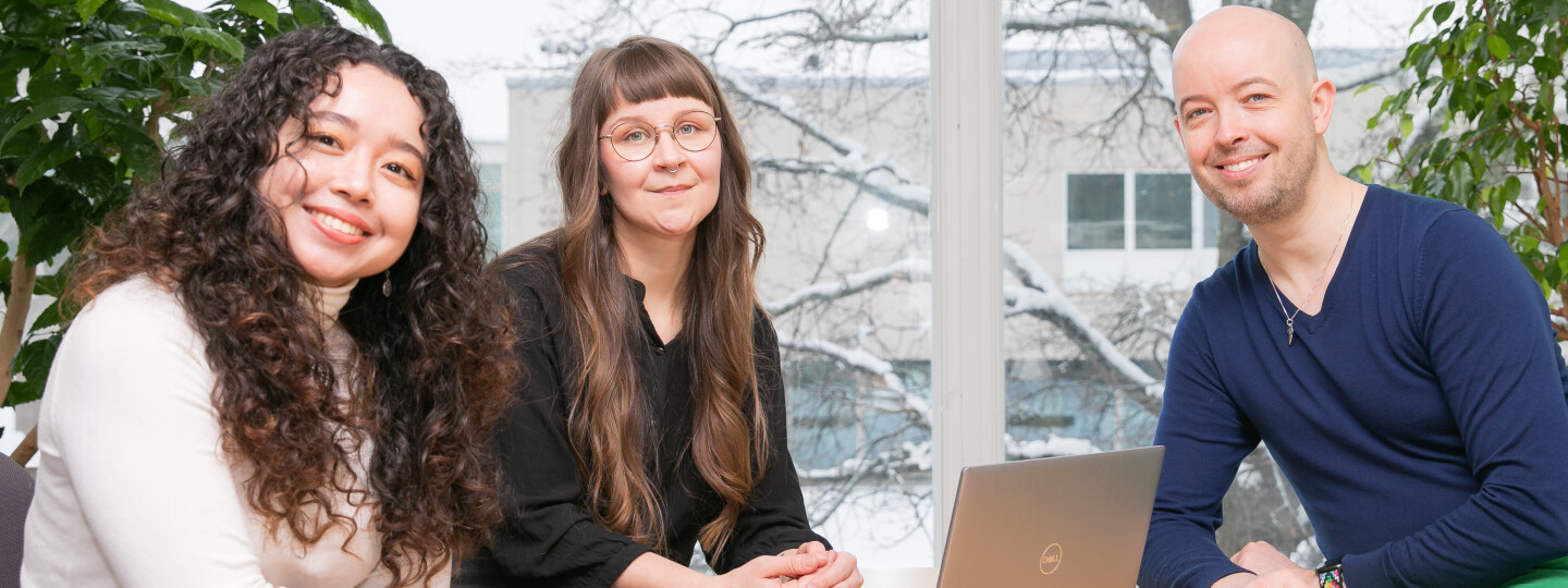 three doctoral researchers sitting at a table smiling