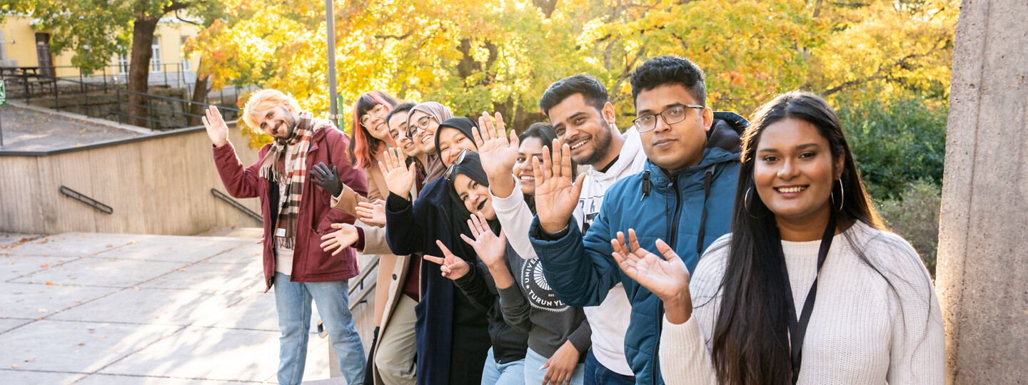 Yliopiston kansainväliset opiskelijalähettiläät rivissä vilkuttamassa kameralle.