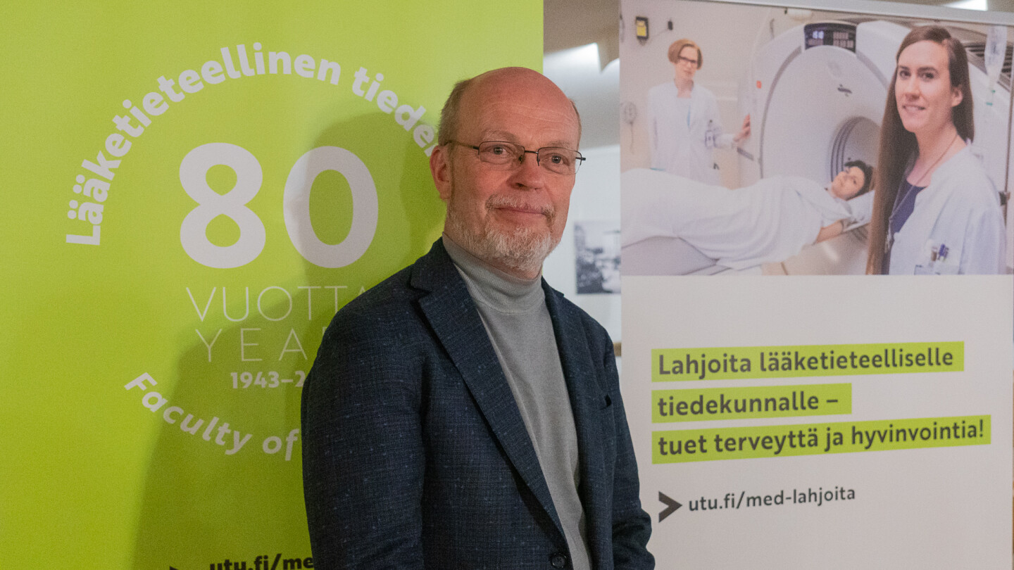 Dekaani Pekka Hänninen tiedekunnan vihreäsävyisten rollupien edessä.