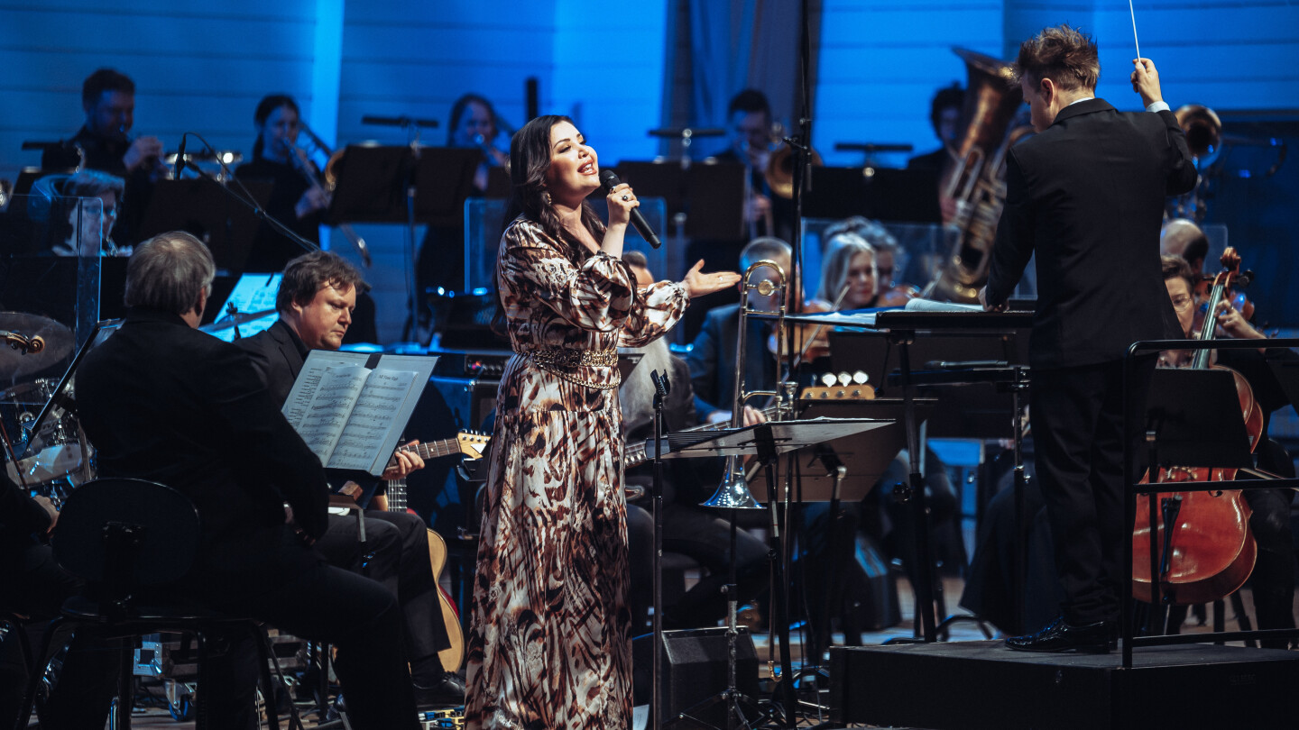 Diandra laulaa pitkässä kullanvärisessä iltapuvussa orkesterin ympäröimänä.