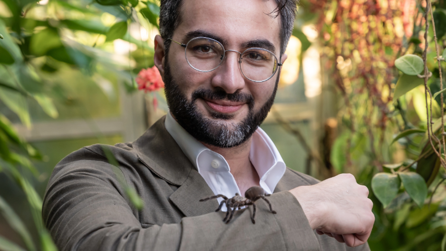 Alireza Zamani pitää käsivarrellaan tarantellaa kasvitieteellisessä puutarhassa.