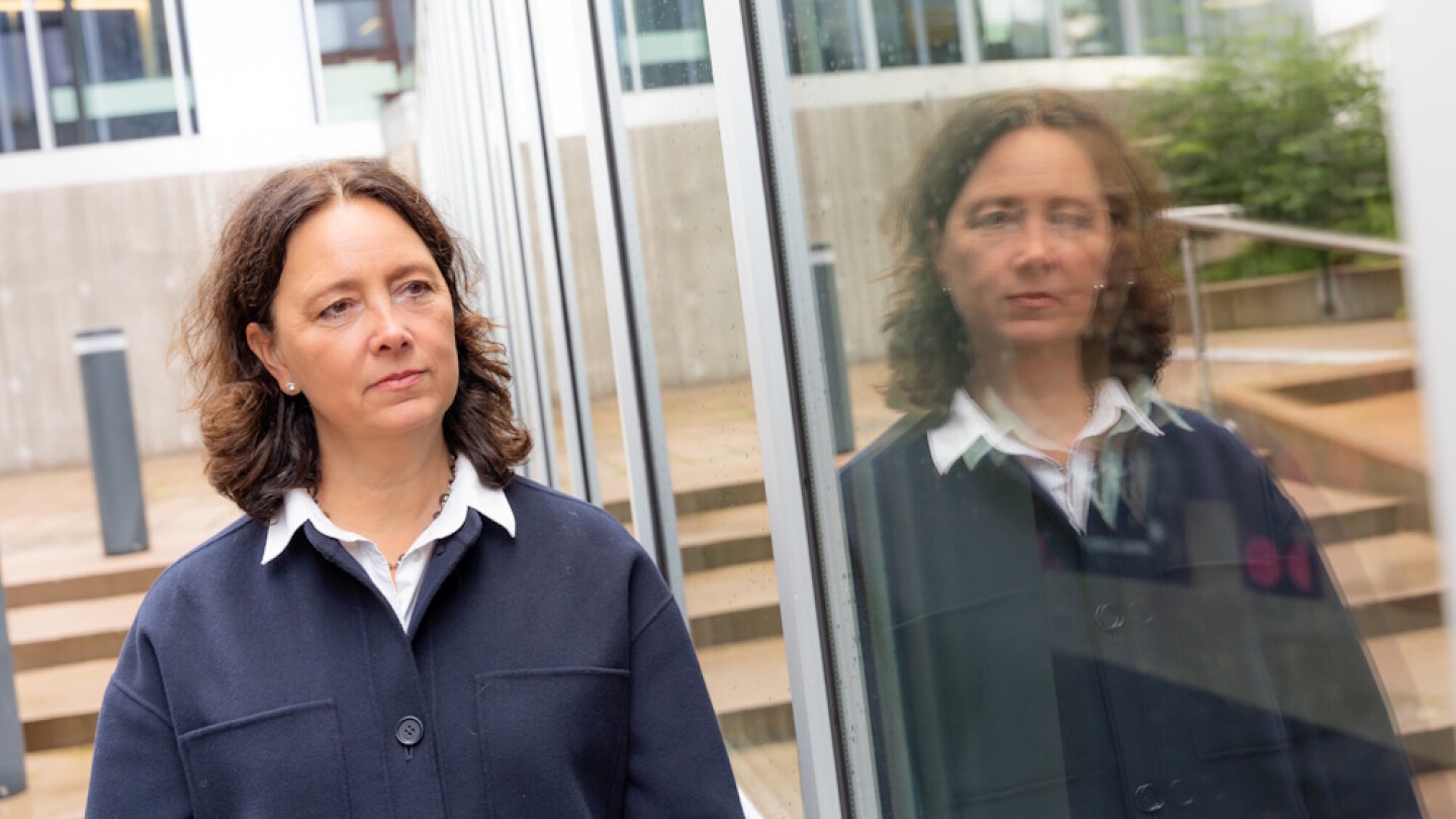 Cecilia Söderberg-Nauclér lähikuvassa ulkona, vieressä lasinen seinä, josta heijastuu hänen kuvansa.