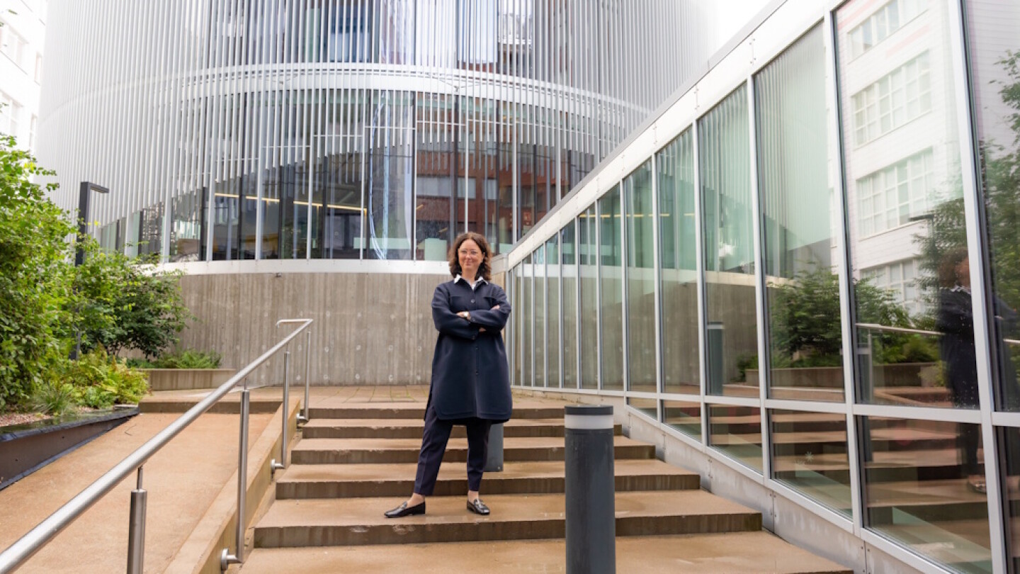 Cecilia Söderberg-Nauclér ulkona rappusilla, taustalla pyöreä lasinen rakennus.