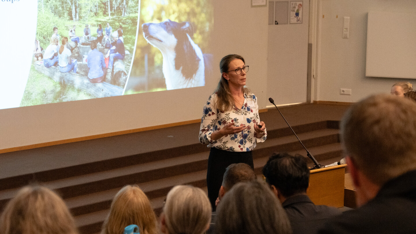 Nora Fagerholm puhuu luentosalissa, taustalla luontokuvia.