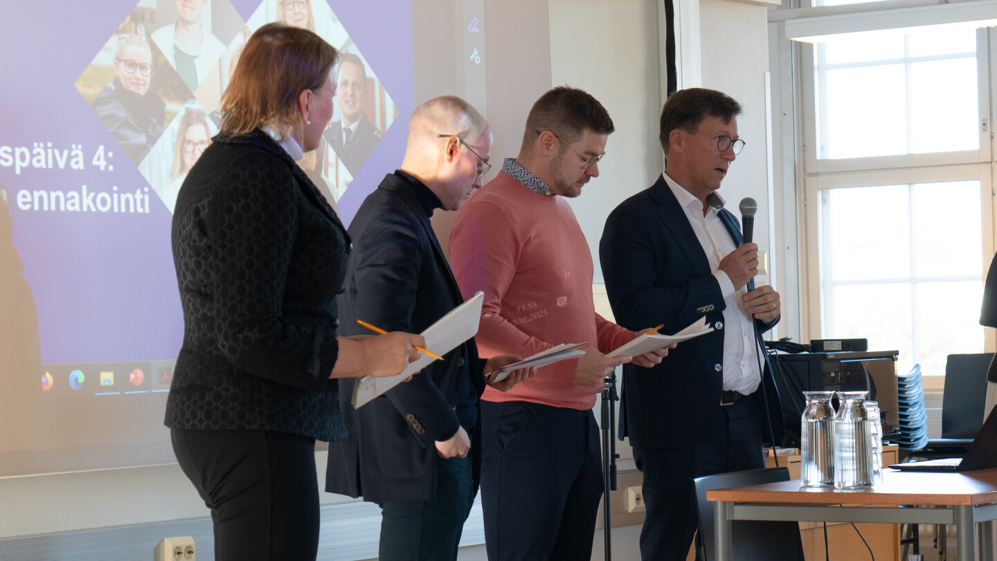 Pirjo Mustonen, Mustonen, Mikko Pietilä, Mikko Pakarinen ja Ville Rajahalme puhumassa salin edessä