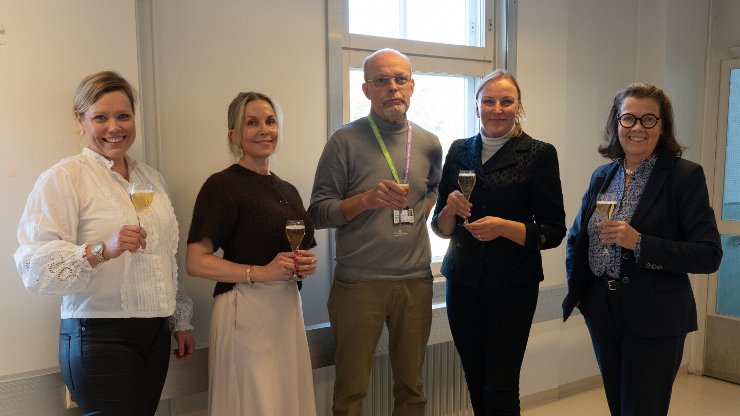 Työryhmä poseeraamassa kuohuviinimaljat kädessään