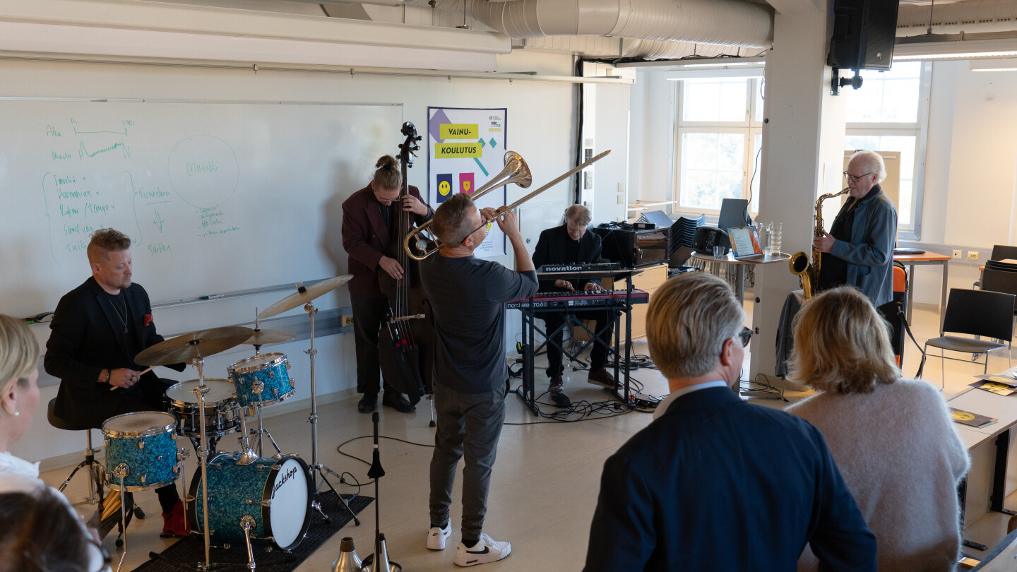 Ihmisiä soittamassa soittimia salin edessä