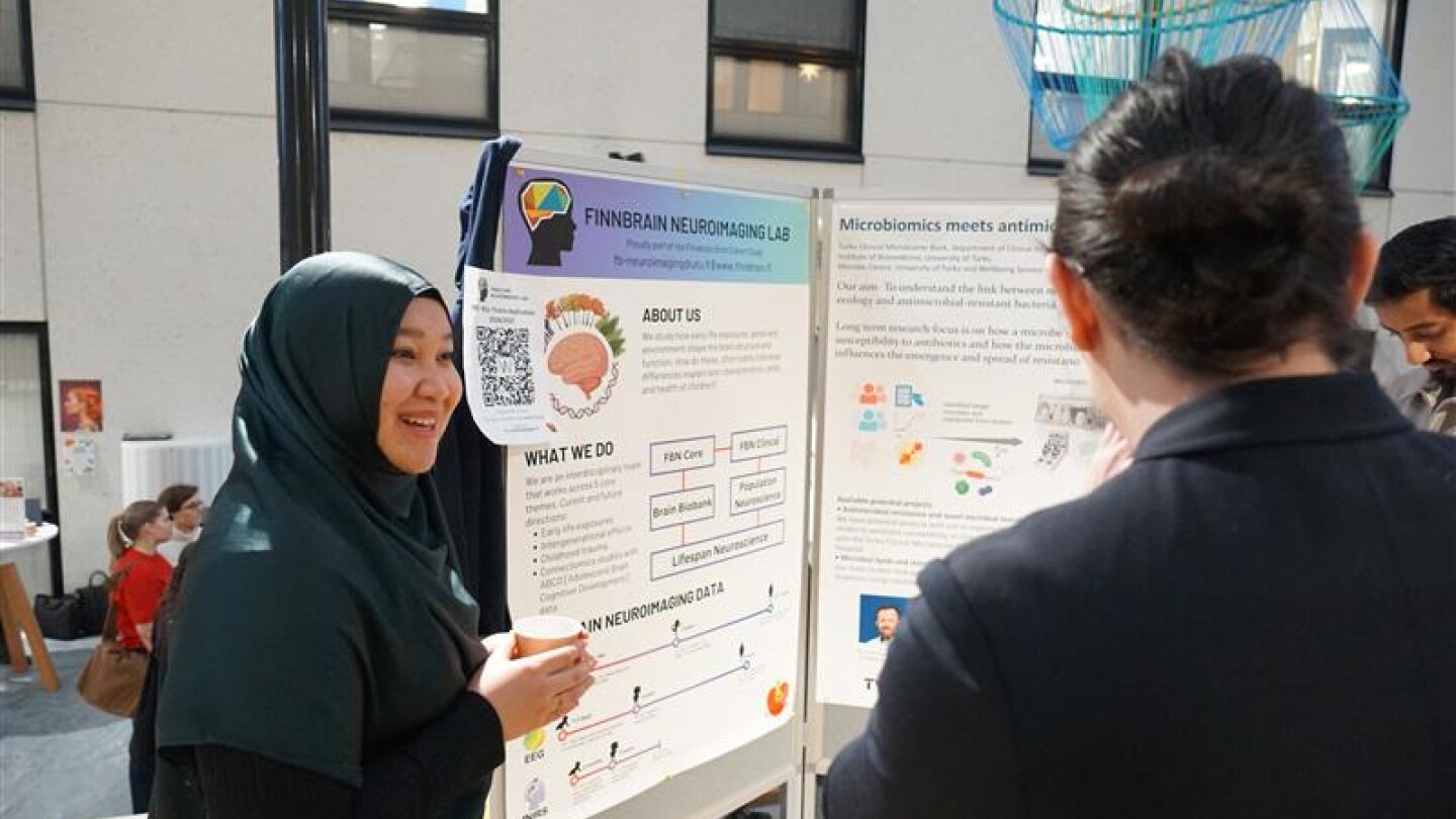 Hilyah keskustelemassa muiden henkilöiden kanssa posterin edustalla